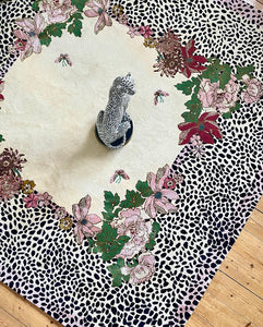 Hand-tufted rug with central floral design in pink, red, and green, surrounded by a black and white leopard print border with pink accents. Available in square and rectangular shapes